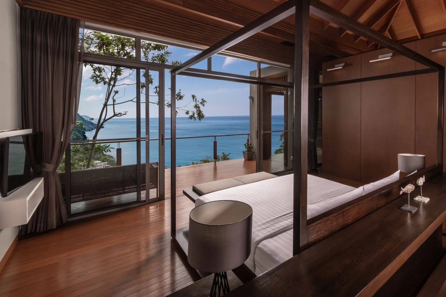 A bedroom with a canopy style bed and a window looking out to the ocean