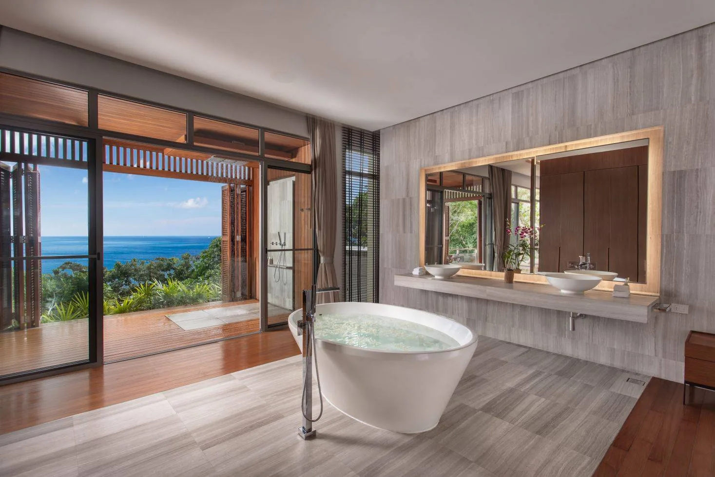 A bathroom with glass doors opening to a deck and a view beyond