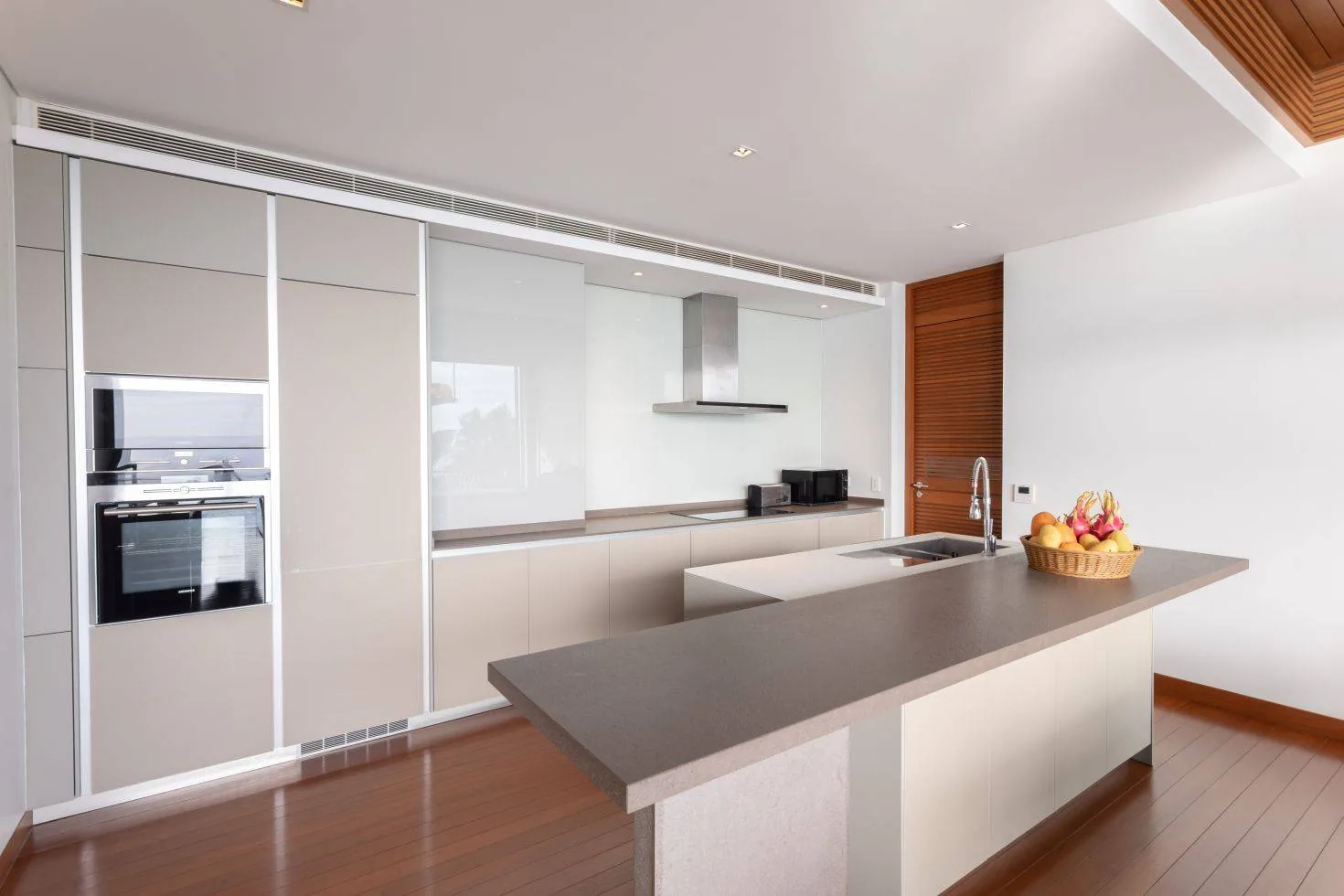 A kitchen counter with an oven and sink built into white cabinetry