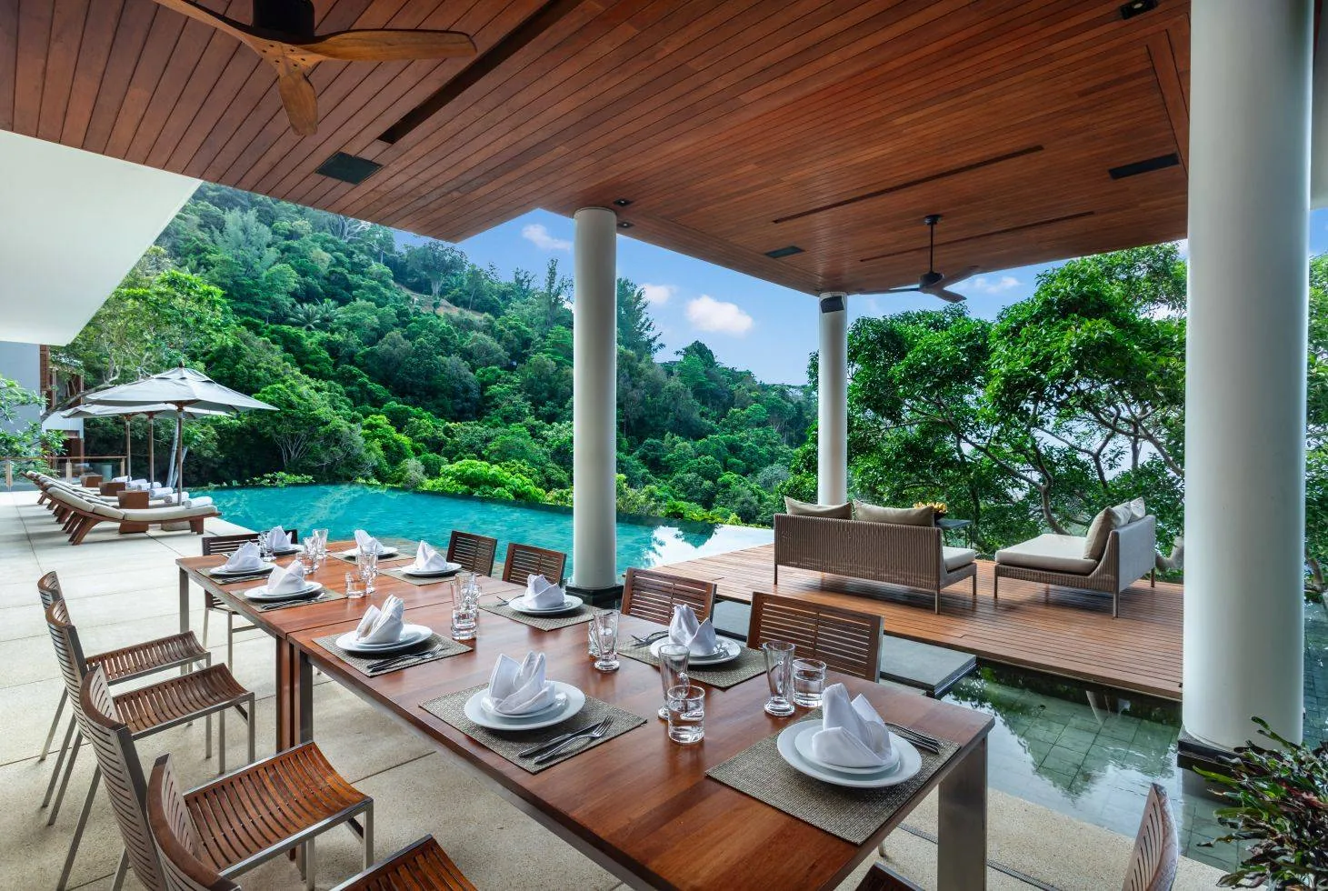 A covered outdoor dining terrace beside the pool, with the table set for a meal