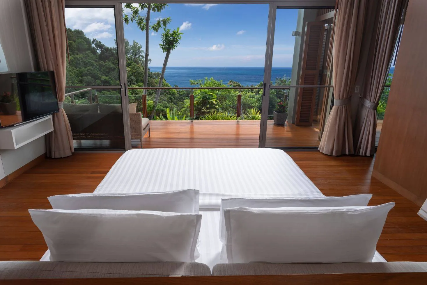 A bedroom with a bed made up in white linen facing a window