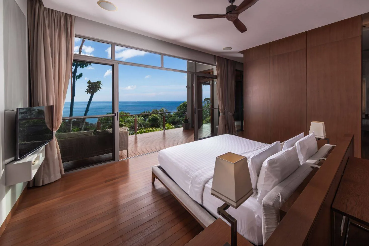 A bedroom with a television unit and a window with a sea view