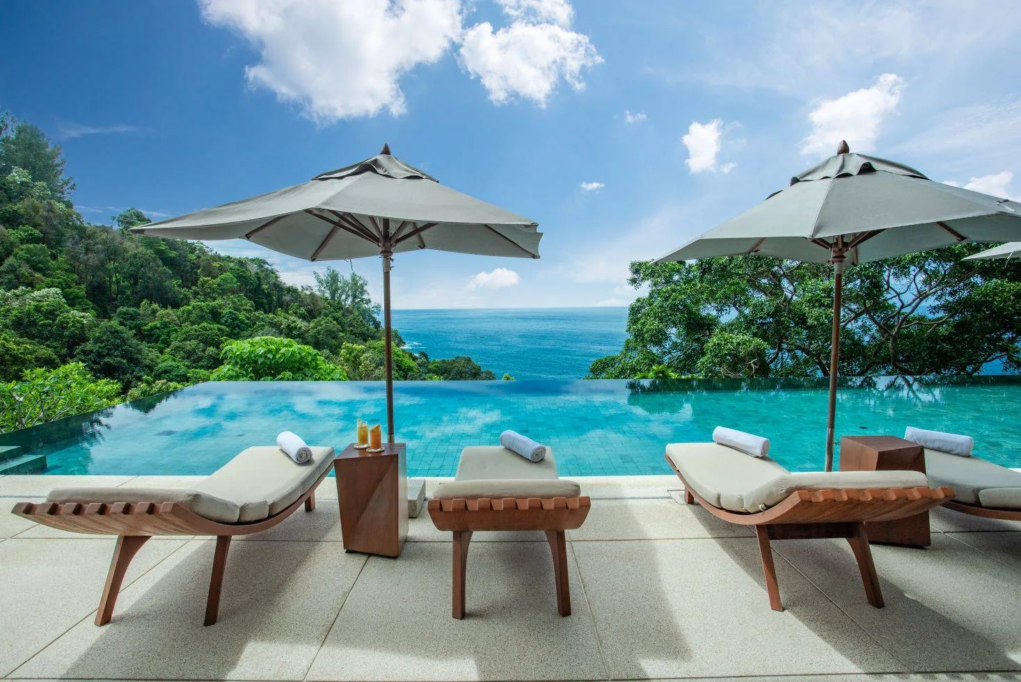 Sun loungers under umbrellas beside an infinity pool overlooking the sea