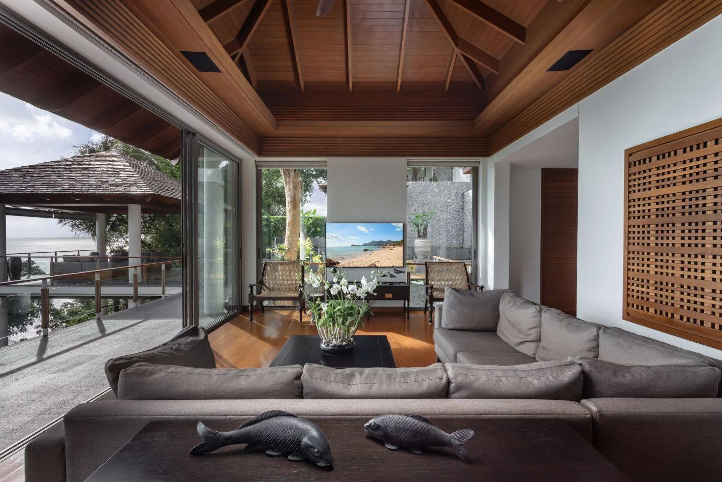 A living room with an L shaped sofa and two fish shaped sculptures on the coffee table