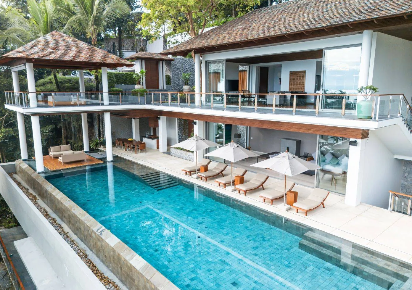 An exterior view of the pool with the villa's tiled roof and surrounding trees