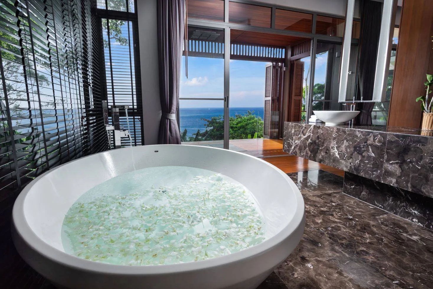 A bathroom with a round soaking tub and a dark stone counter