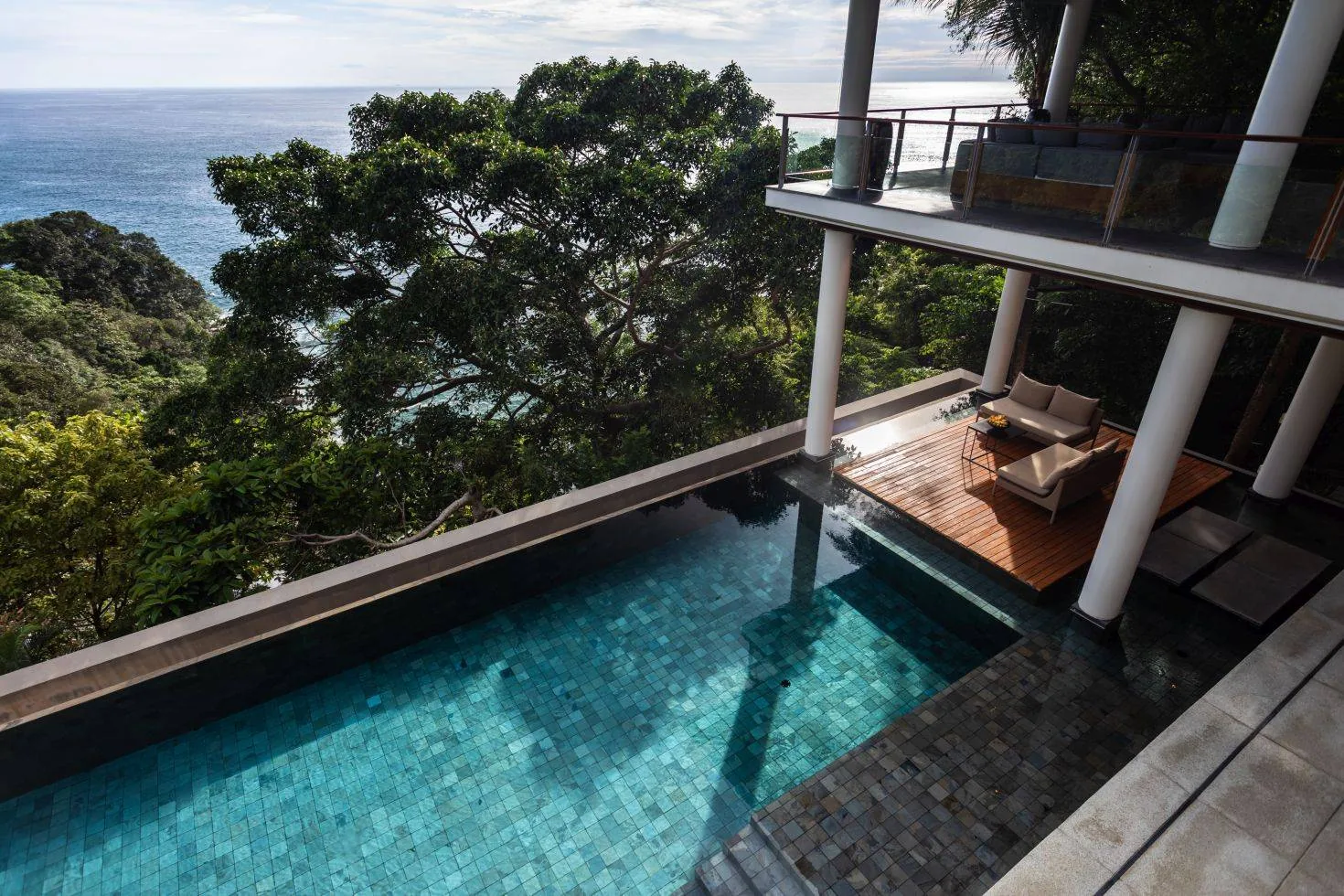 An exterior view of an infinity pool with a glimpse of the sea beyond