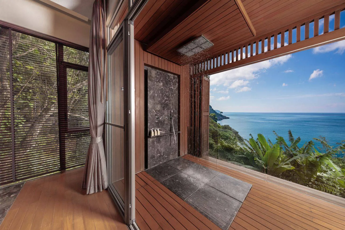 An outdoor shower open to a forest and sea view