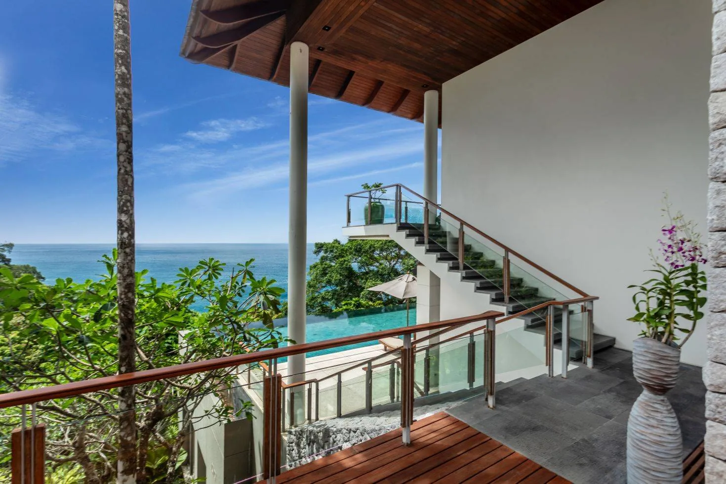 An exterior stairway and deck with the sea and forest beyond