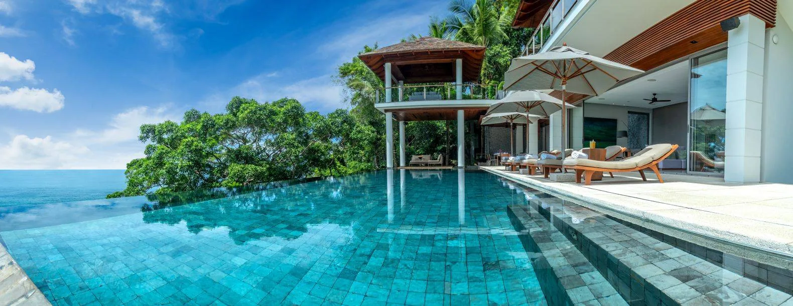 An aerial view of the pool with the villa building and an open sided pavilion