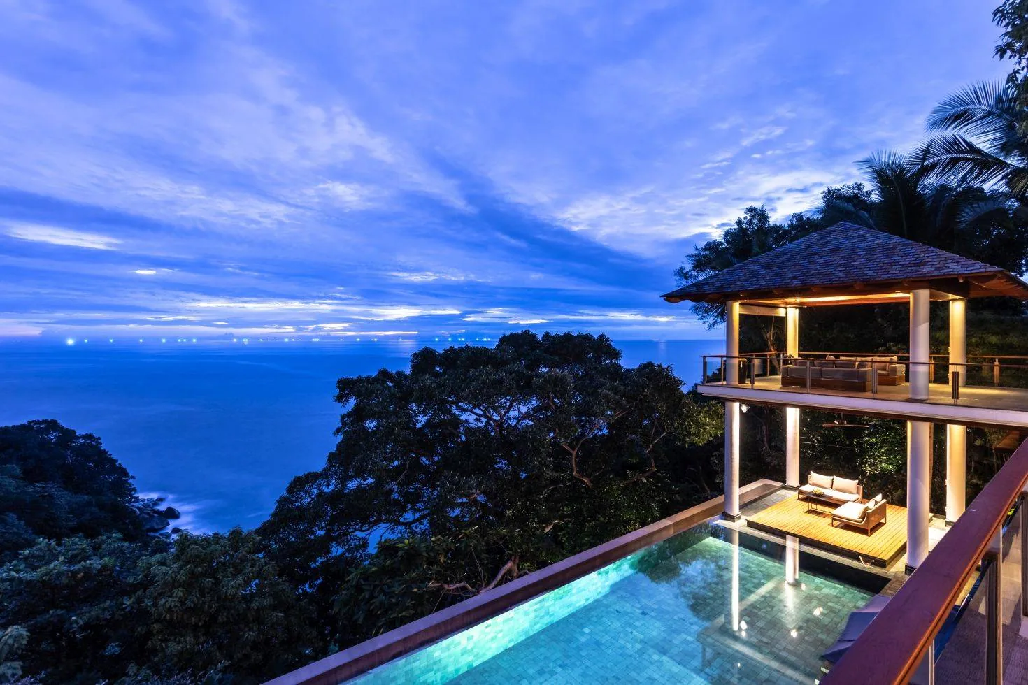 The villa exterior with the pool lit at dusk